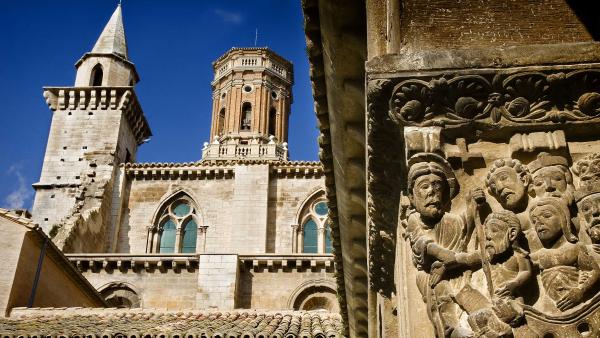 Capitel en primer plano y al fondo la parte alta de la fachada de la catedral de Tudela